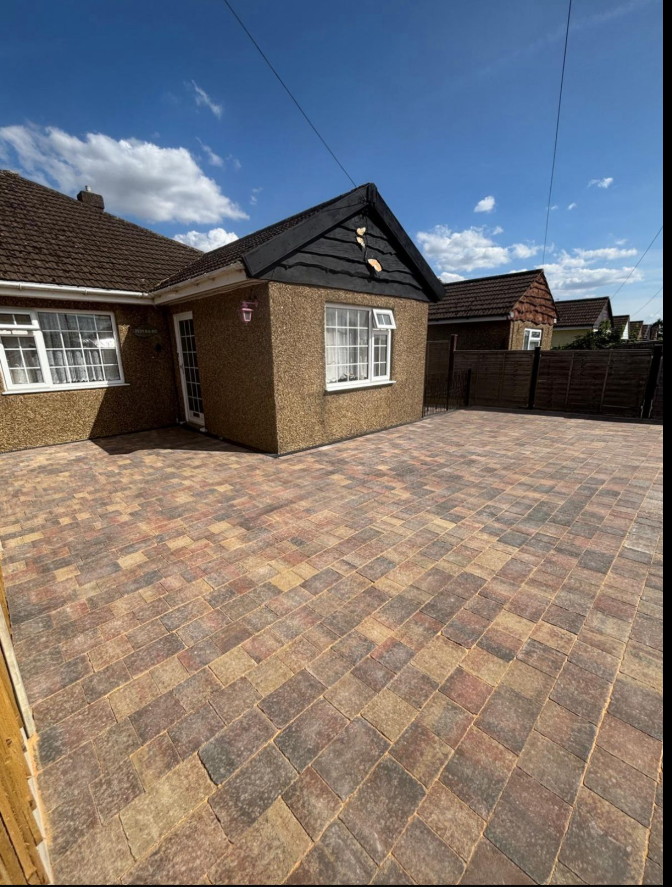 Large multi-tone block paved driveway in front of a bungalow